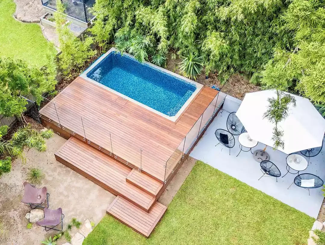 50 Semi-Inground Pool Designs That Transform Any Backyard Into Your Personal Paradise A Pool With a Weather-Resistant Deck and Glass Wall